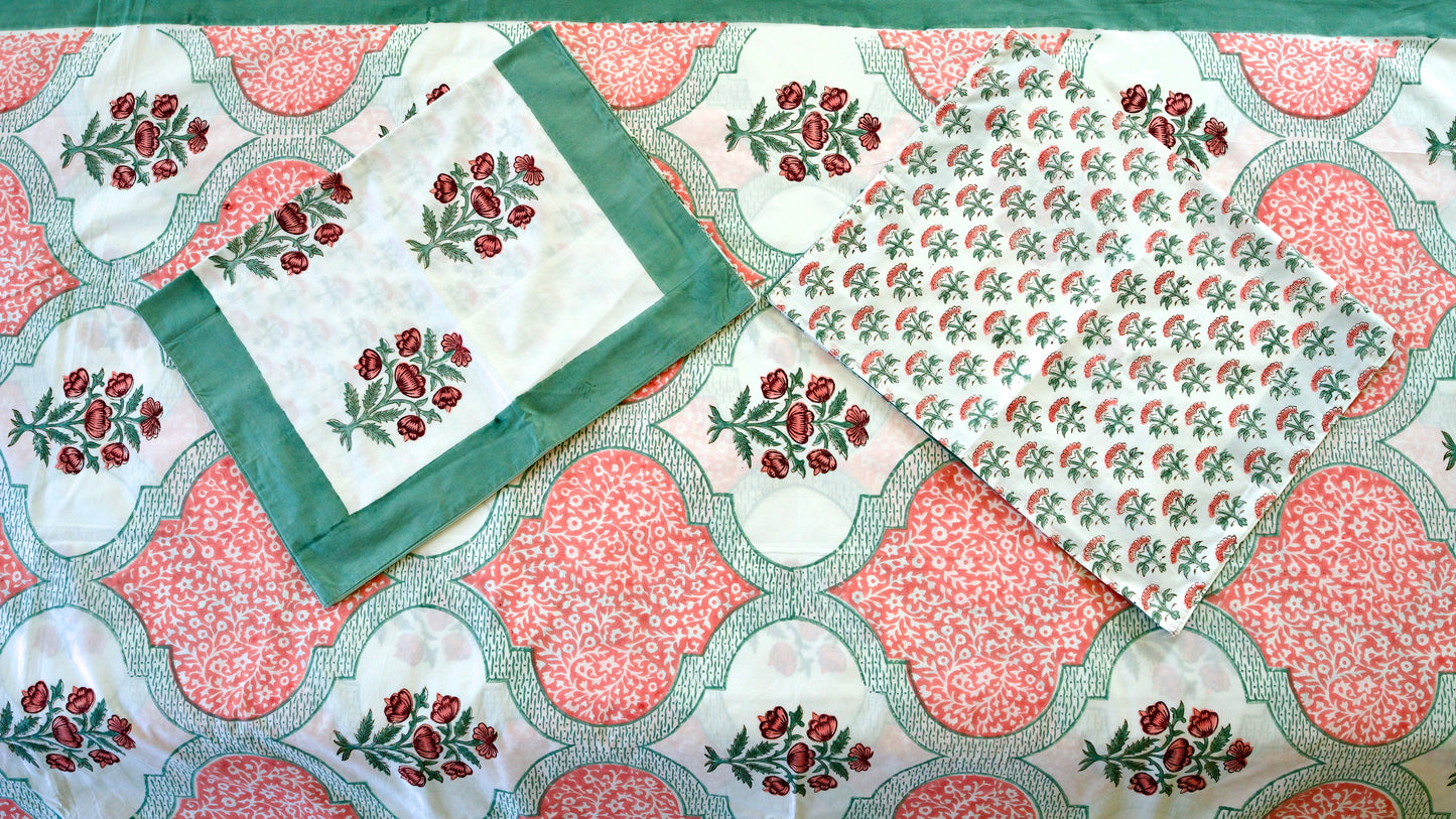 Coral Lattice hand block printed organic cotton bedsheet with red floral clusters, green leaves, coral lattice panels, white base, and matching floral patterned pillowcases