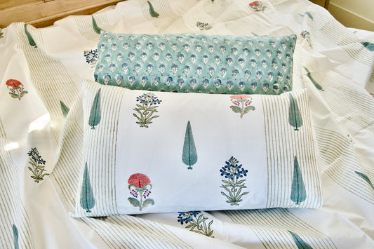 Two decorative pillows with floral patterns on a bedspread.