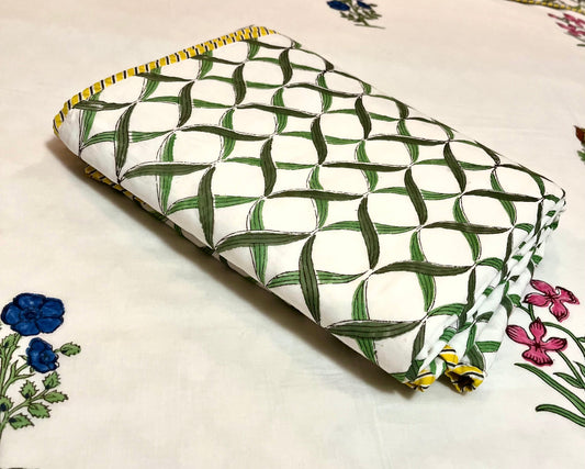Green and white patterned pouch on a floral bedspread