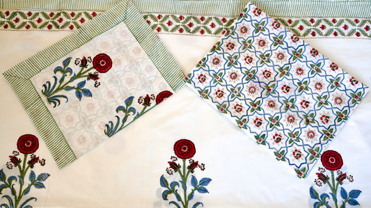 Redwood Trellis hand block printed organic cotton bedsheet with crimson florals, blue leaves, green striped border, and trellis-patterned pillowcases in red, blue, and green
