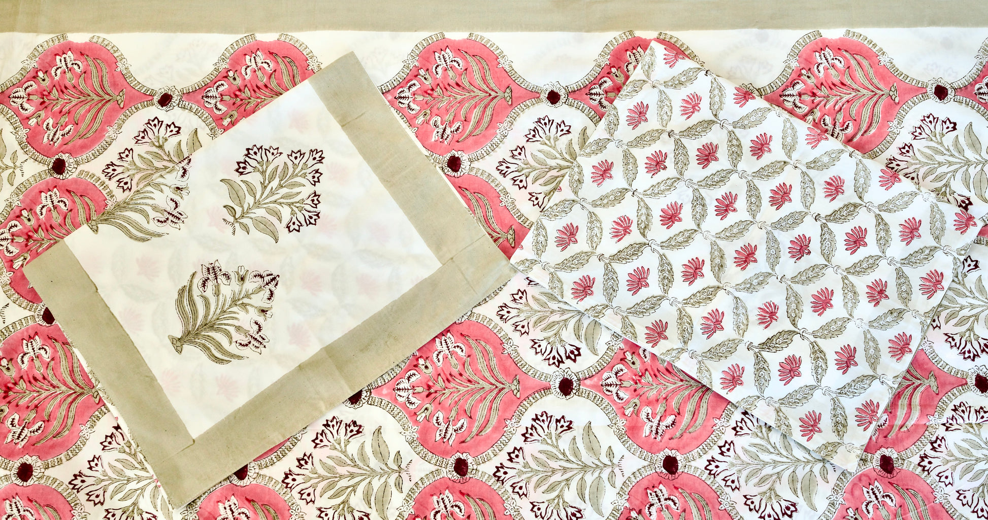 Rosette Arch hand block printed organic cotton bedsheet with olive-green and pink leafy motifs framed in red arches on a white base, paired with beige-bordered and vine-patterned pillowcases