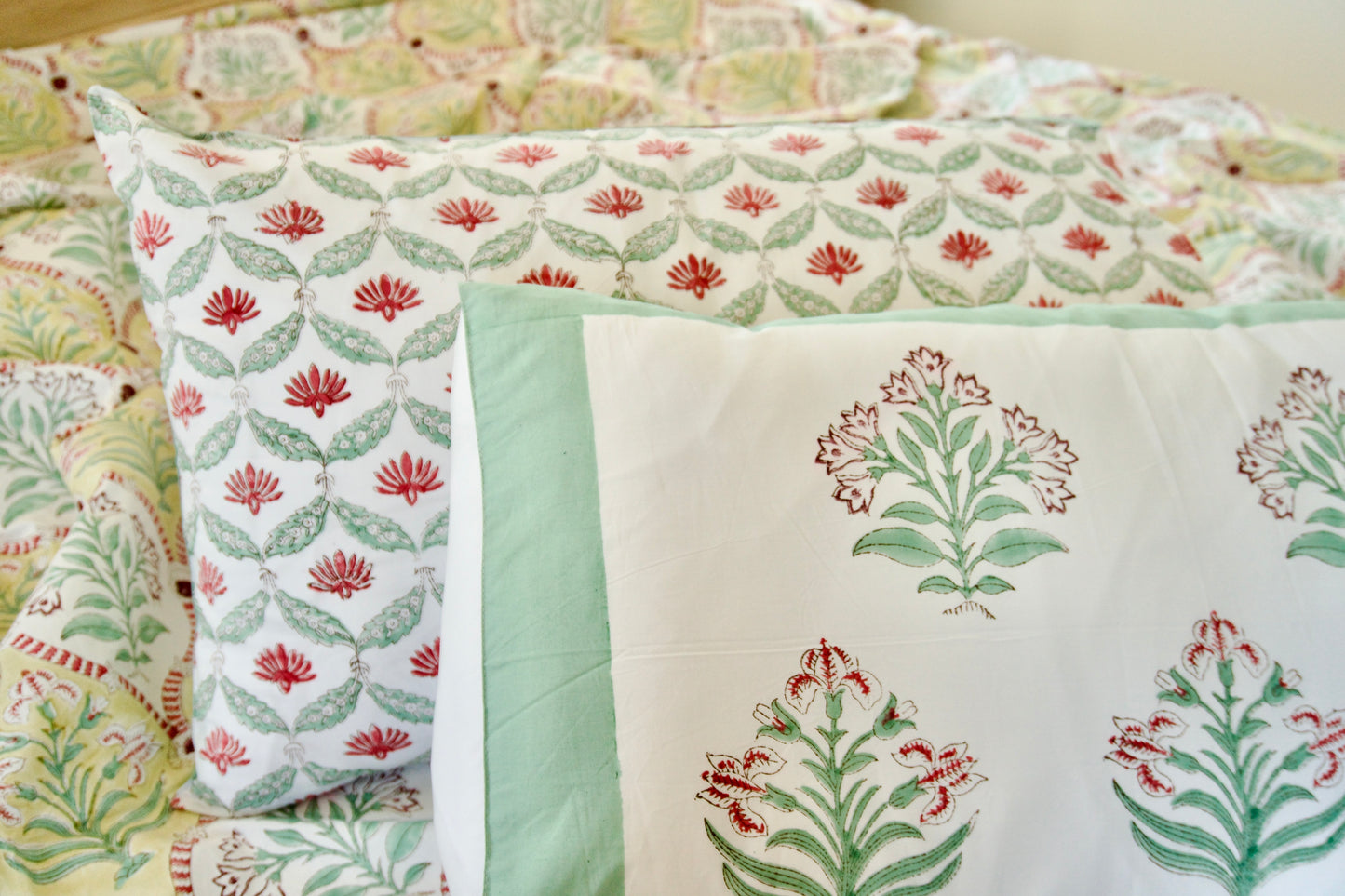 Floral patterned bedding set with green and red colors on a bed.