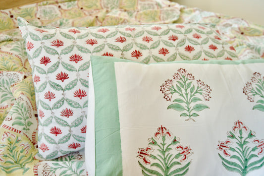 Floral patterned bedding set with green and red colors on a bed.